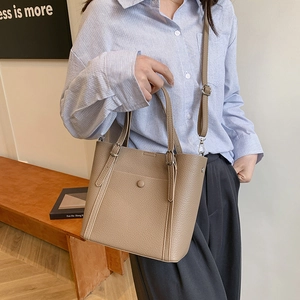 Brown faux leather tote bag with top handles and adjustable strap in lifestyle setting