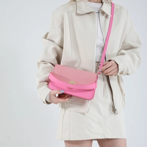 Fuchsia woven leather crossbody bag with round gold buckle on white outfit model