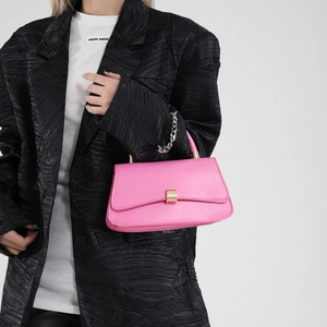 Borsa a tracolla rosa minimalista con fibbia dorata e catena d'argento su blazer nero