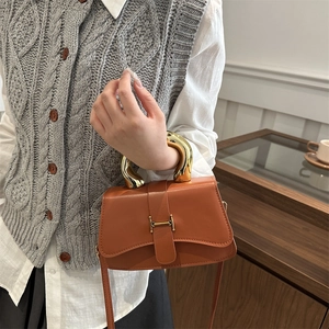 Braune Lederhandtasche mit goldenem U-Griff und H-Schnalle in elegantem Lifestyle-Ambiente