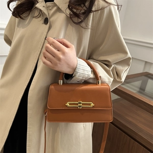 Caramel brown leather shoulder bag with a unique gold chain lock and top handle