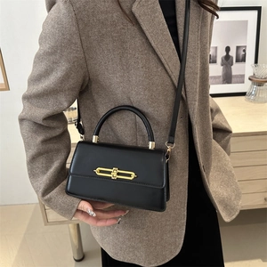 Elegant black leather baguette bag with gold metal lock and adjustable shoulder strap