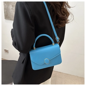 Detail view of sky blue PU leather crossbody bag with silver oval clasp and top handle