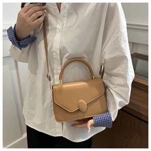 Close-up of minimalist khaki crossbody bag with oval gold buckle and top handle