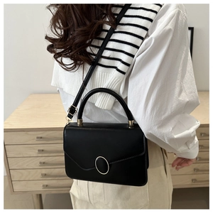Side view of a black leather crossbody bag with golden clasp and adjustable strap
