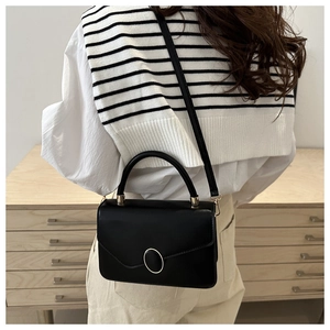 Detailed view of a black minimalist retro crossbody bag with a round metal buckle