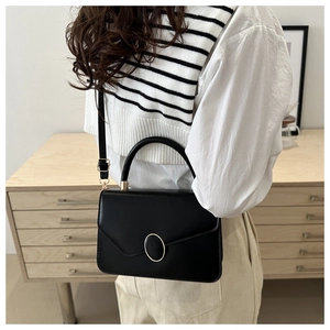 Detail of minimalist black crossbody bag with gold buckle on a stylish model