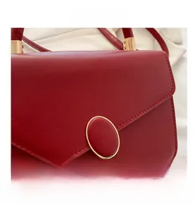 Detail view of burgundy leather small square bag with golden oval magnetic closure