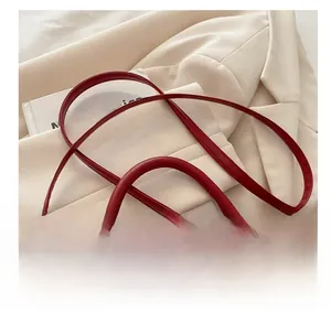 Close-up of adjustable red synthetic leather shoulder strap with gold hardware buckle