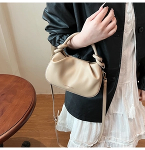 Detail of beige pleated cloud bag showing knotted handle and FASHION & BAGS logo