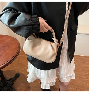 Detail of the ring handle and logo on a beige ruched cloud bag for women