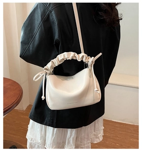 Detailed back view of a creamy white pleated handbag worn with a black leather jacket