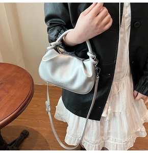 Detail of silver pleated dumpling bag with metallic finish and long shoulder strap