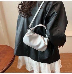 Detail of silver pleated dumpling bag with knot handle and adjustable shoulder strap