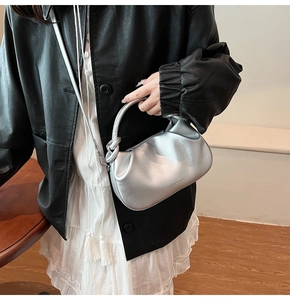 Detail showing metallic silver pleated cloud bag with knotted handle and shoulder strap
