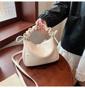 Detail of beige pleated handle bag with drawstring accents and adjustable strap