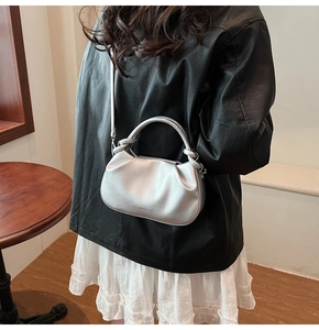 Silver pleated cloud bag worn by model in a cozy indoor setting showing shoulder strap