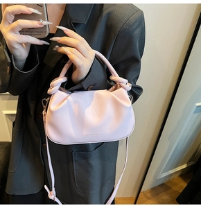 Detail of soft pink pleated dumpling bag with knotted handle and fashion lettering