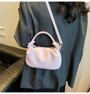 Detail shot of pale pink ruched cloud bag with FASHION & BAGS logo on grey blazer
