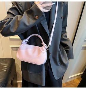 Detail of light pink pleated cloud bag featuring knotted handle and thin shoulder strap