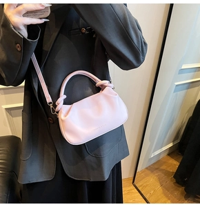Detail of pink pleated cloud bag with knotted handle and fashion text logo on smooth leather