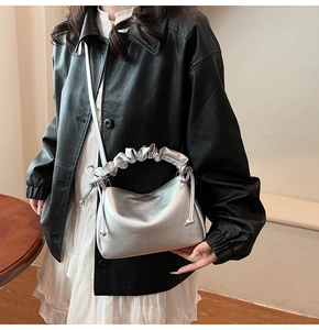 Detail of silver metallic scrunchie handbag with drawstring accents and fashion text