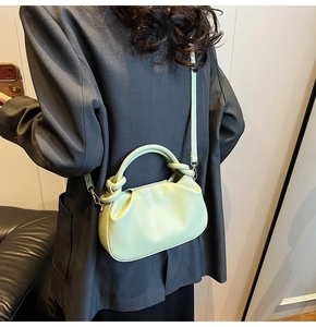 Close-up of a mint green pleated cloud bag showing soft faux leather and strap detail