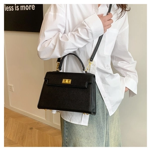 Detail of black cross-grain leather bag with gold buckle and removable shoulder strap