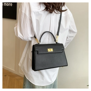 Detail of elegant black textured handbag with iconic gold twist lock on a fashion model