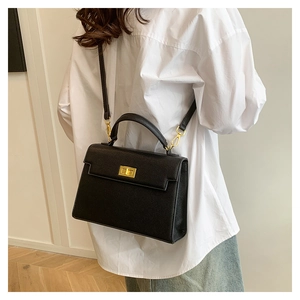 Model wearing a black lychee texture crossbody bag with gold hardware and a classic handle