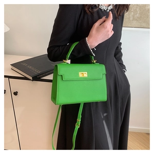 Fashionable bright green Kelly-style handbag with gold twist lock on a black dress
