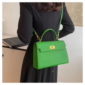 Model view of a bright green trapezoidal handbag with gold twist lock and shoulder strap