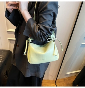Detail of mint green ruched shoulder bag showing drawstring knot and fashion logo text