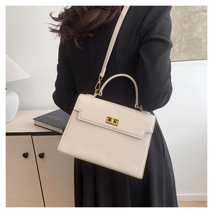 Crossbody view of a cream leather trapezoid bag with gold twist lock on a model