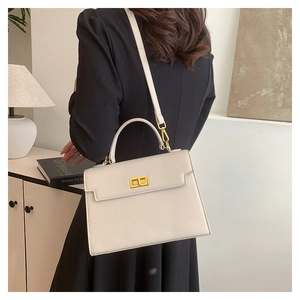 Detail view of a white lychee grain leather handbag with gold clasp and shoulder strap