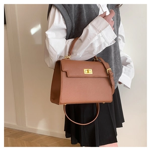 Detail view of caramel brown handbag with gold twist lock and protective metal feet