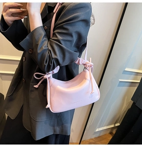 Detail of pink PU leather handbag showing unique ruffled strap and fashion text logo