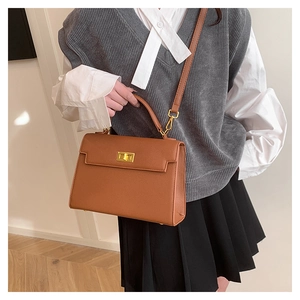 Classic brown textured leather handbag with gold twist lock shown in a lifestyle setting