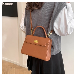Brown lychee leather crossbody bag with gold hardware shown on a female model