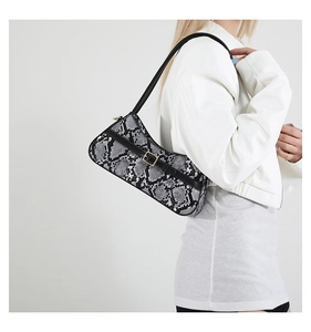 Close-up of a snake-print baguette bag with black strap and golden buckle detail