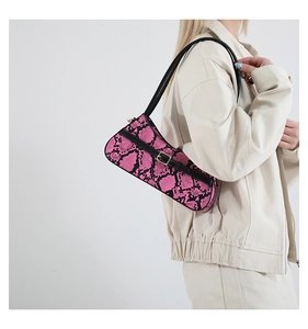 Chic pink and black snake pattern baguette bag worn by model on a white background