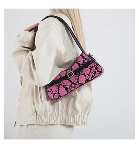 Detail of pink and black snakeskin baguette bag with gold buckle on shoulder
