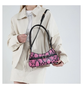 Close-up of snake skin pattern texture and metal buckle on stylish faux leather baguette bag