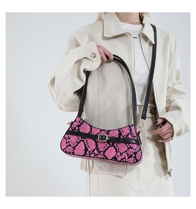 Close-up of pink and black snake skin texture on baguette bag with golden hardware