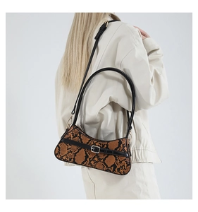 Detail of vintage faux snakeskin bag featuring golden buckle and black leather strap trim