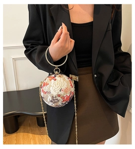 Detail of floral embroidery and rhinestone gold handle on spherical evening bag