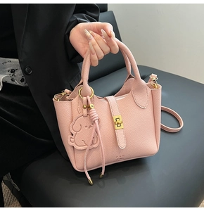 Detail of light pink pebble leather bucket bag with puppy charm and golden clasp
