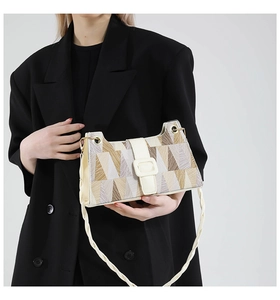 Detail of geometric pattern shoulder bag with a woven rope strap on a black blazer