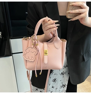 Detailed shot of pink lychee leather bucket bag with gold lock and dog charm