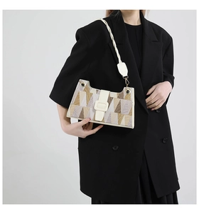 Detail of geometric pattern underarm bag with white strap and gold hardware